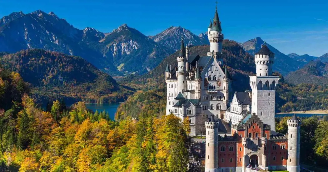 Neuschwanstein Castle with alpine mountains and Alpsee lake in the backdrop Neuschwanstein Castle with alpine mountains and Alpsee lake in the backdrop